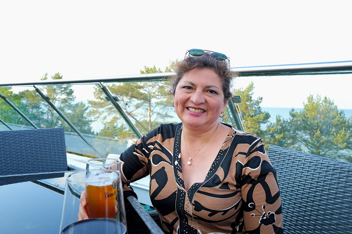 Lächelnde Frau mit Getränk auf der Terrasse der Arkona Sky Bar, Symbolbild für positiven Erfahrungsbericht eines Stammgastes.