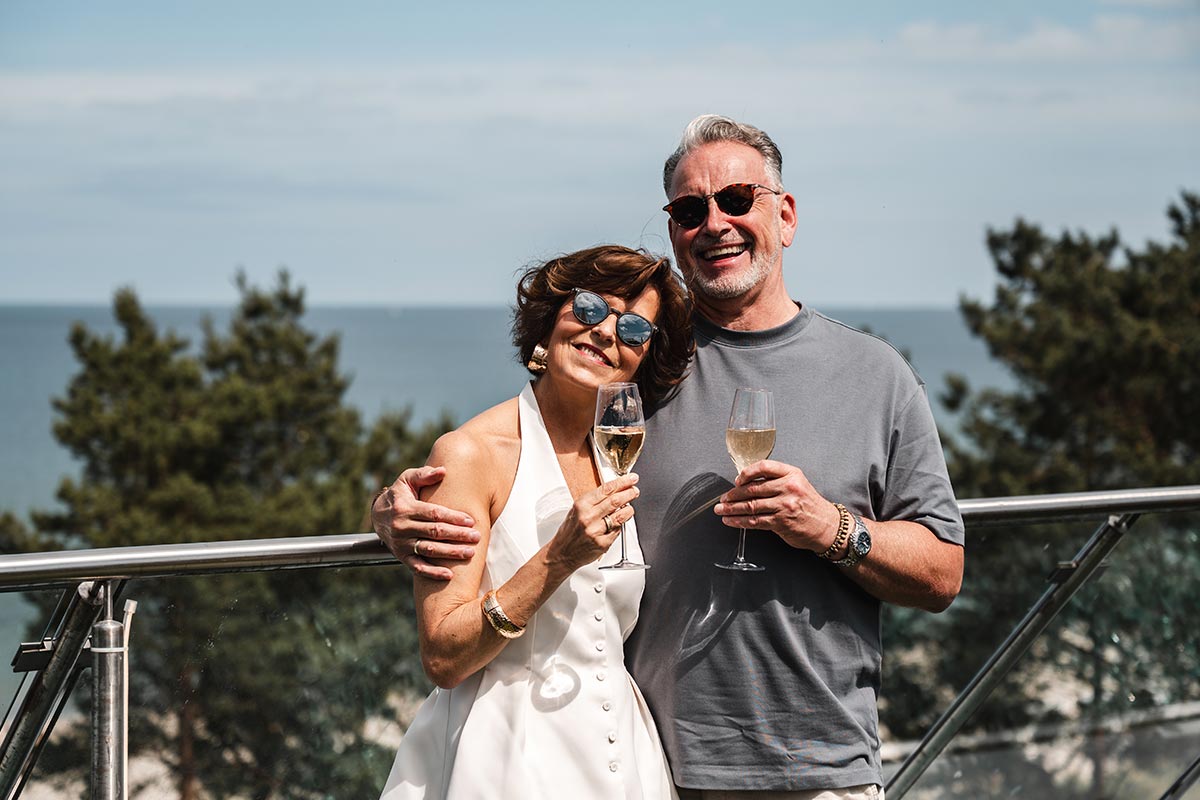 Paar stößt mit Sekt auf der Terrasse der Sky Bar in Binz mit Blick auf die Ostsee an.