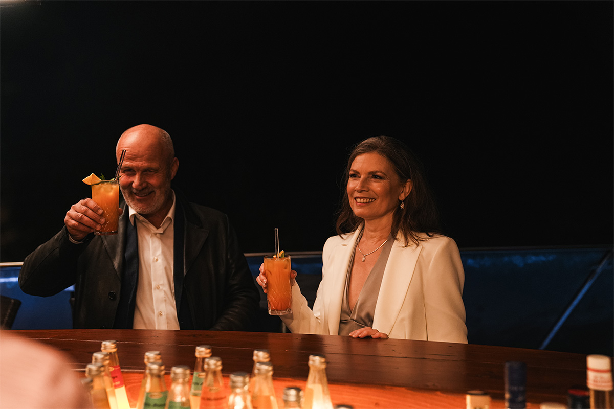 Paar hebt am Abend an der Bar der Sky Bar Binz zwei Cocktails mit Orangenscheibe